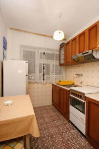 a kitchen with wooden cabinets and a white refrigerator at Apartments with a parking space Selce, Crikvenica - 5531 in Selce