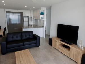 a living room with a black leather couch and a flat screen tv at Oceanic 19 - linen not included in Forster