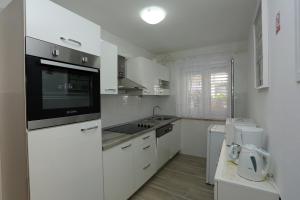 una cocina con armarios blancos y un aparato negro en Apartments with a parking space Supetar, Brac - 5385, en Supetar