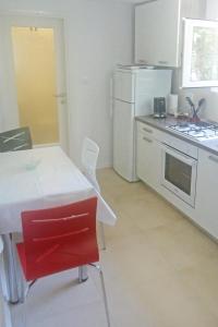 a white kitchen with a table and a white refrigerator at Apartment Selce 5531b in Selce