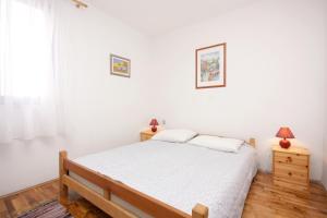a white bedroom with a bed and two lamps at Apartments with a parking space Porat, Krk - 5322 in Malinska
