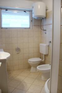 a bathroom with a toilet and a sink and a window at Apartments with a parking space Baska, Krk - 5407 in Baška