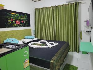 Cette chambre comprend un lit et un rideau vert. dans l'établissement B&B NAMO PHUKET, à Kathu