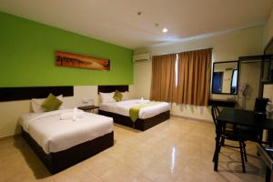 a hotel room with two beds and a table at Golden Roof Hotel Falim Ipoh in Ipoh
