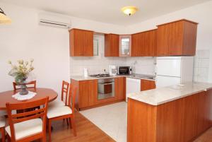 una cocina con armarios de madera y una mesa con mesa. en Apartments with a swimming pool Novi Vinodolski - 5479, en Novi Vinodolski
