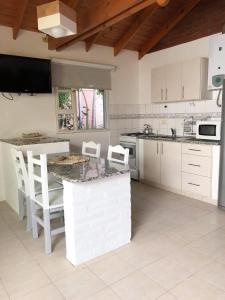 cocina con armarios blancos, mesa y sillas en Tehuelches del sur en Puerto Madryn