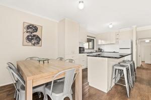 a kitchen with white cabinets and a wooden table and chairs at Panoscape in Sunset Strip