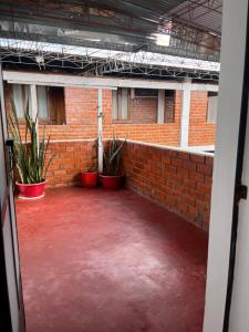 an empty room with a brick wall and potted plants at Hospedaje Familiar Laos in Oxapampa
