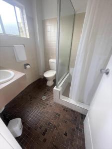 a bathroom with a shower and a toilet and a sink at Forster Motor Inn in Forster