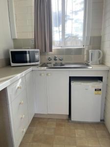 uma cozinha com um micro-ondas e um lavatório em Forster Motor Inn em Forster