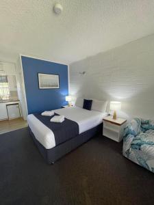 a bedroom with a large bed and a couch at Forster Motor Inn in Forster