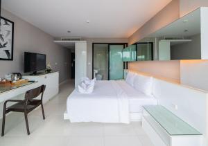 a bedroom with a large white bed and a desk at Serenotel Pattaya in Pattaya Central