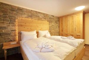 a bedroom with a large white bed with a stone wall at Allgäuer Kräuteralm in Oberstaufen