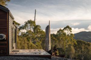 a cabin with a deck and a view of the forest at Tiny Escapes Cradle Valley in Moina