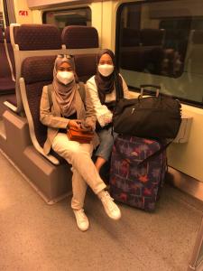 duas pessoas com máscaras sentadas num comboio com bagagem em Rose Guest House em Kota Bharu