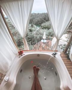 una persona en una bañera en una habitación con vistas en Levit Glamping - Hotel Guatapé ADULTS ONLY en Guatapé