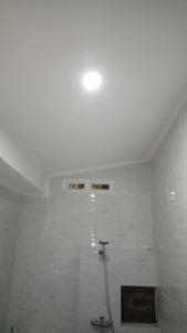 a white bathroom with a shower with a hose at Mulia Home Stay in Nusa Dua
