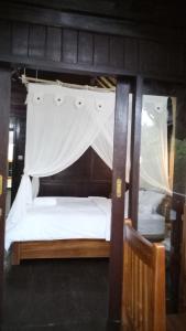a bedroom with a bed with a canopy at Mulia Home Stay in Nusa Dua