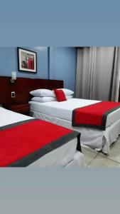 two beds in a hotel room with red and white sheets at Hotel Boutique Malibu Los Sueños in Tigre