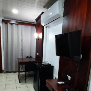 een hotelkamer met een televisie en een bureau met een tafel bij Hotel Boutique Malibu Los Sueños in Tigre