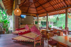 un patio con sofá, mesas y sillas en Prayatna Villas en Ubud