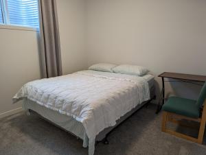 a bedroom with a bed and a desk and a chair at Livingston Howse Haven - A simple & cozy private two-bedroom basement suite with free parking in Calgary