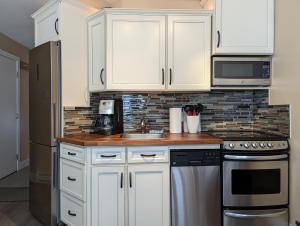 a kitchen with white cabinets and a sink at Steps to All New Gondola, Sleeps 4 with Free Parking in Whistler