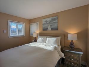 a bedroom with a white bed and two windows at Steps to All New Gondola, Sleeps 4 with Free Parking in Whistler