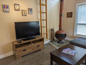 a living room with a flat screen tv on a wooden stand at Steps to All New Gondola, Sleeps 4 with Free Parking in Whistler