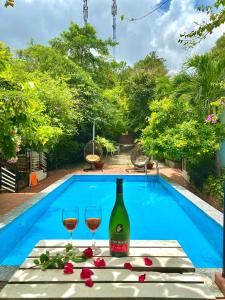 Ngoc Hanh Bungalow Phu Quoc في فو كووك: زجاجة من النبيذ وكأسين على طاولة بالقرب من حمام سباحة