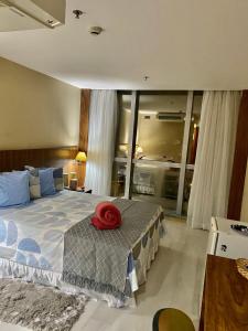 ein Schlafzimmer mit einem Bett mit einem roten Hut darauf in der Unterkunft Flat encantador com piscina e área de lazer in Brasilia