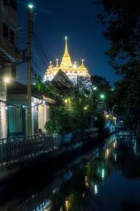 um edifício iluminado à noite com um rio em Non House Hostel บ้านนอนโฮสเทล em Banguecoque