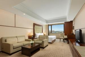 a hotel room with a bed and a television at Millennium Hotel Wuxi in Wuxi
