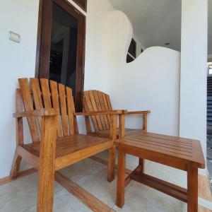 two wooden chairs and a bench in a room at Putra Boyan Cottages in Gili Trawangan