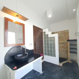 baño con lavabo negro y espejo en Putra Boyan Cottages, en Gili Trawangan