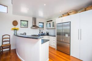 a kitchen with white cabinets and a stainless steel refrigerator at The Deck Tideways in Sorrento