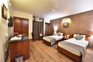 a hotel room with two beds and a desk at Tekareesinn in Lucknow
