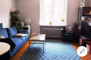 een woonkamer met een blauwe bank en een tafel bij Quiet Central Room in Stockholm