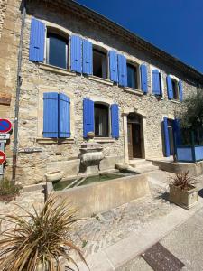 a stone building with blue shutters on it at La Fontaine de Vinsobres in Vinsobres