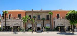 a building with palm trees in front of it at Hotel Moderno in Assisi