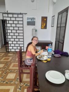 Una donna seduta a un tavolo con un piatto di cibo di Back Packers Cochin Villa a Cochin