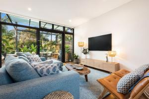 un salon avec un canapé bleu et une télévision dans l'établissement Byron Beachside Bliss - with pool & beach access, à Byron Bay