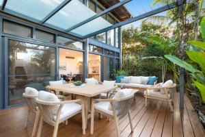 une véranda avec une table et des chaises en bois dans l'établissement Byron Beachside Bliss - with pool & beach access, à Byron Bay