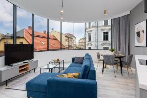 a living room with a blue couch and a large window at Apartament Prestige Centrum in Bielsko-Biała