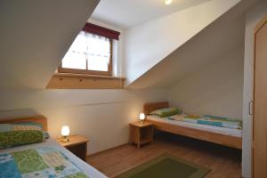 a attic room with two beds and a window at Ferienwohnungen Haus Rachel in Neuschönau