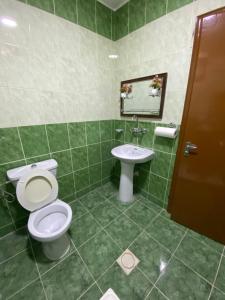 a green tiled bathroom with a toilet and a sink at Hustle's look in Wadi Musa