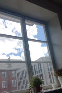 a window with two potted plants and a view of a building at Quiet Central Room in Stockholm