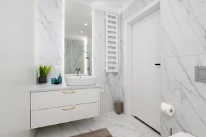 Baño blanco con lavabo y espejo en Apartamenty Prestige Centrum, en Bielsko-Biala