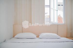 a bed with two pillows in a bedroom with a window at DManggo Guest House Syariah RedPartner in Tasikmalaya