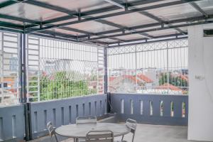 a table and chairs in a room with windows at DManggo Guest House Syariah RedPartner in Tasikmalaya